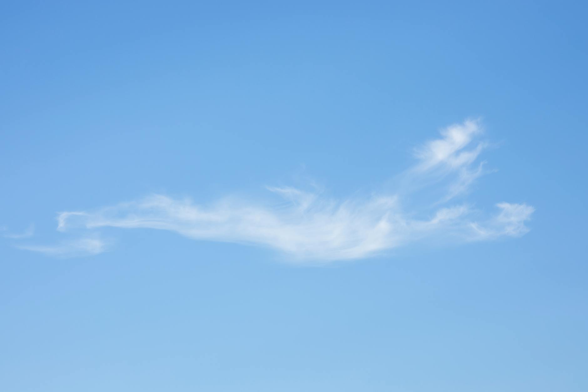 Pojedyncza pierzasta chmura na błękitnym niebie w spokojny dzień