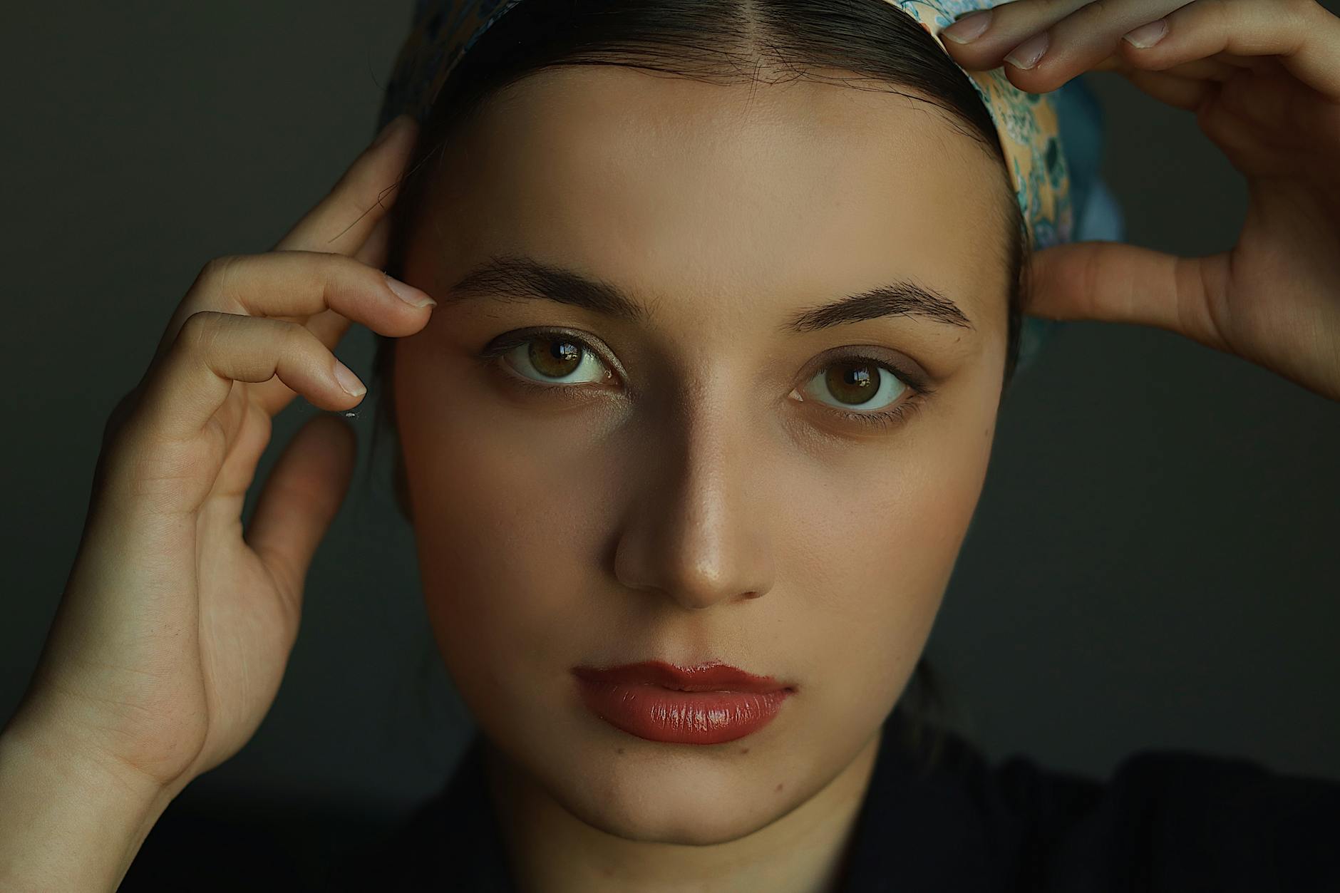 Zbliżenie poważnej kobiety z dłońmi opartymi na głowie