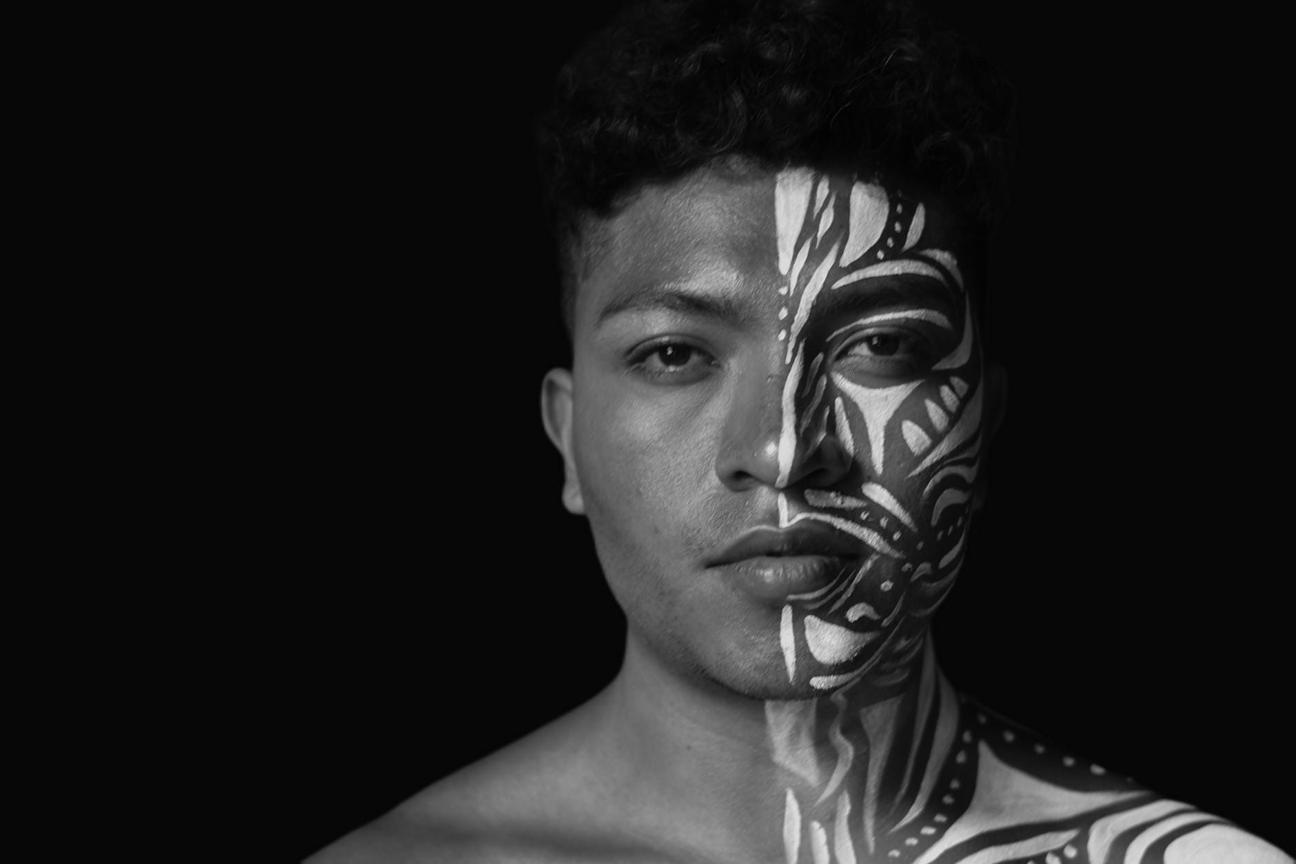 Czarno-biały portret mężczyzny w studyjnym kadrze z plemiennym makijażem