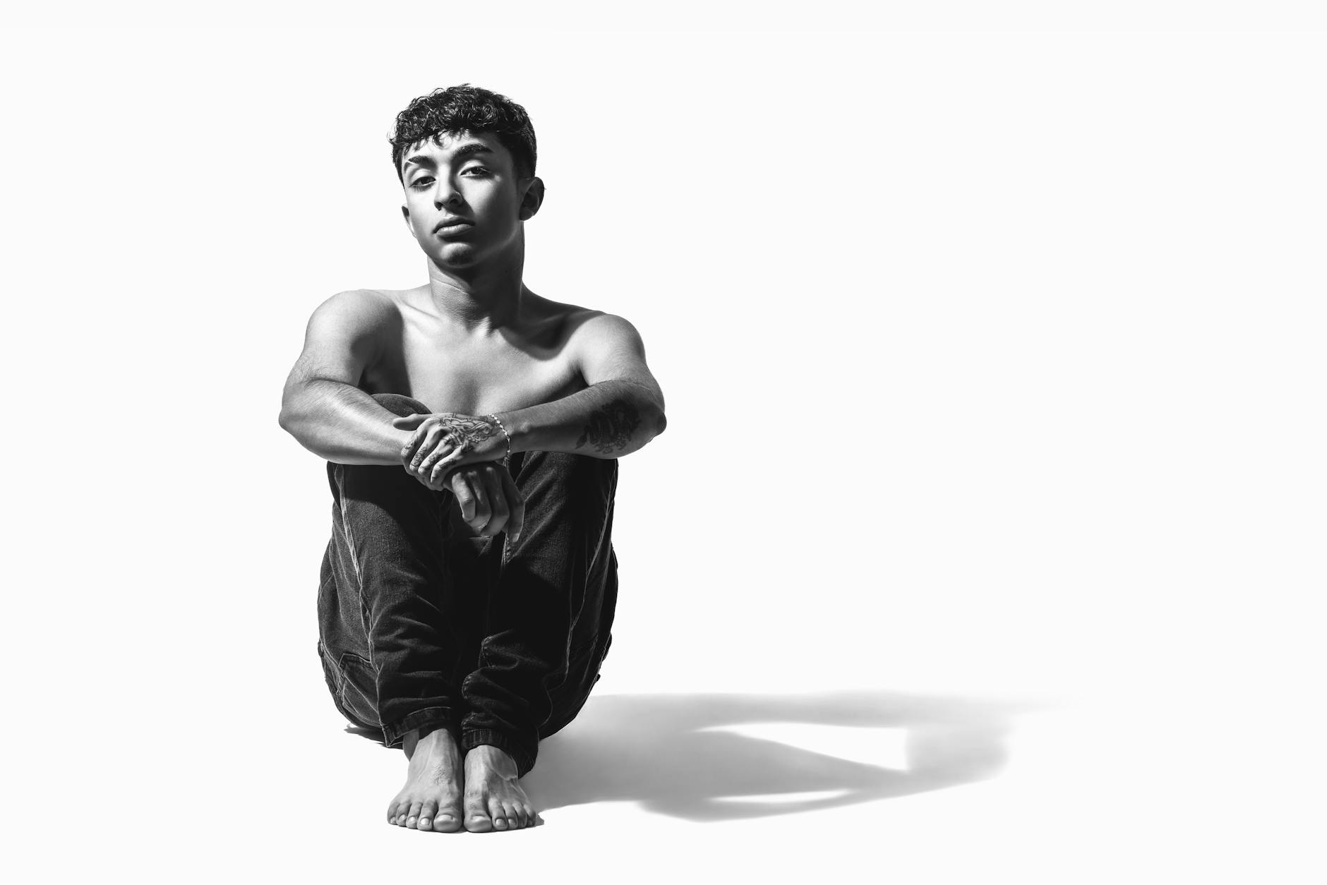 Czarno-biały portret młodego mężczyzny siedzącego samotnie na podłodze