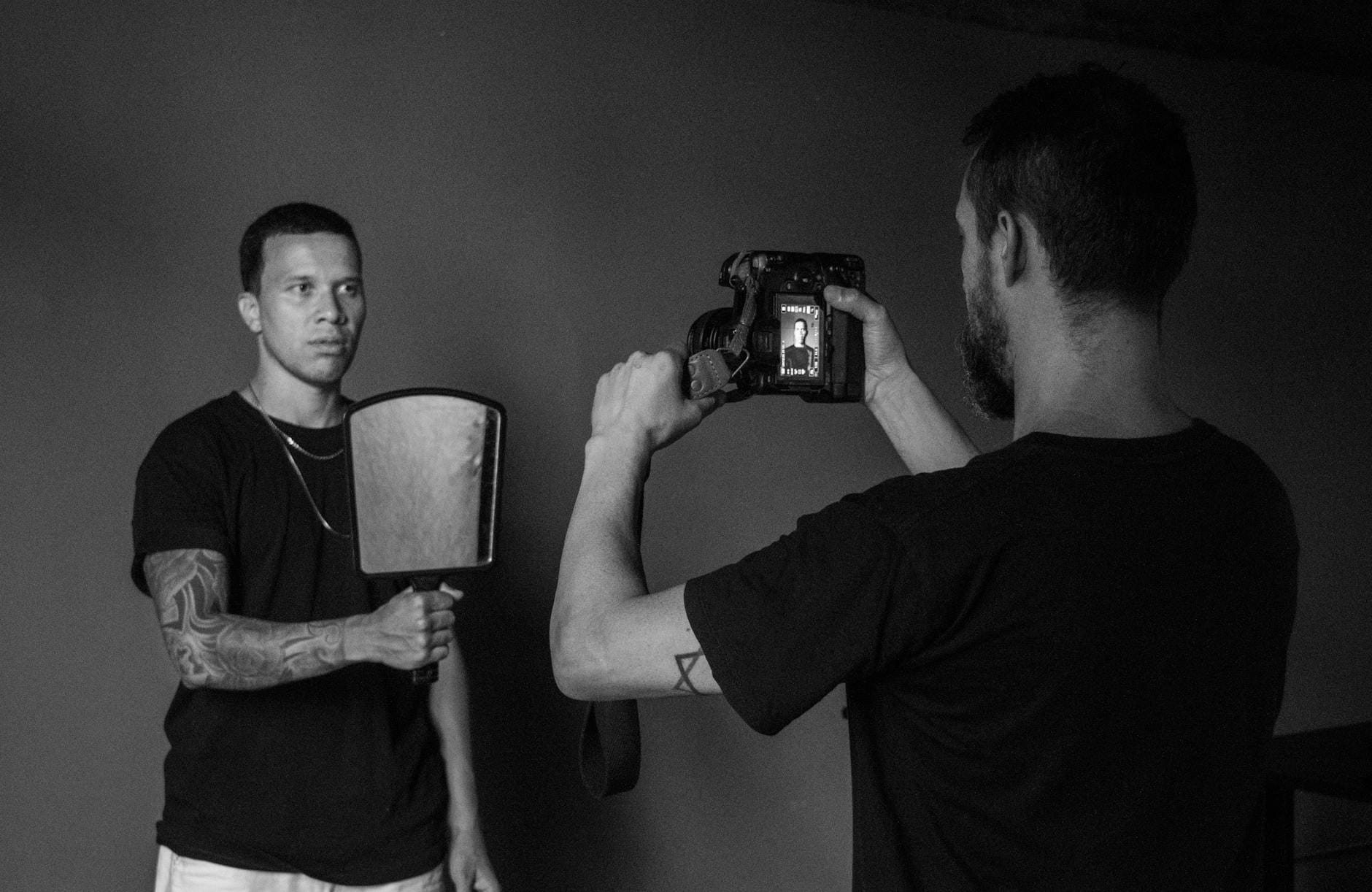 Fotograf w studiu robi czarno-biały portret mężczyzny z blendą