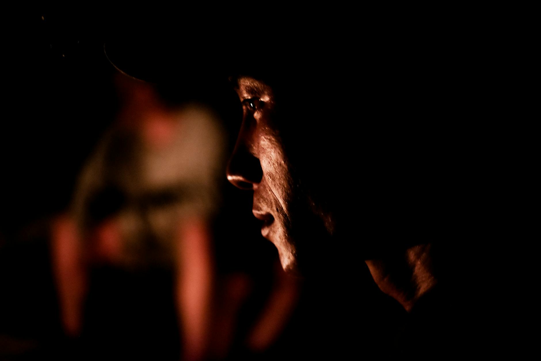 Męski profil oświetlony ostrym światłem bocznym w ciemnym kadrze