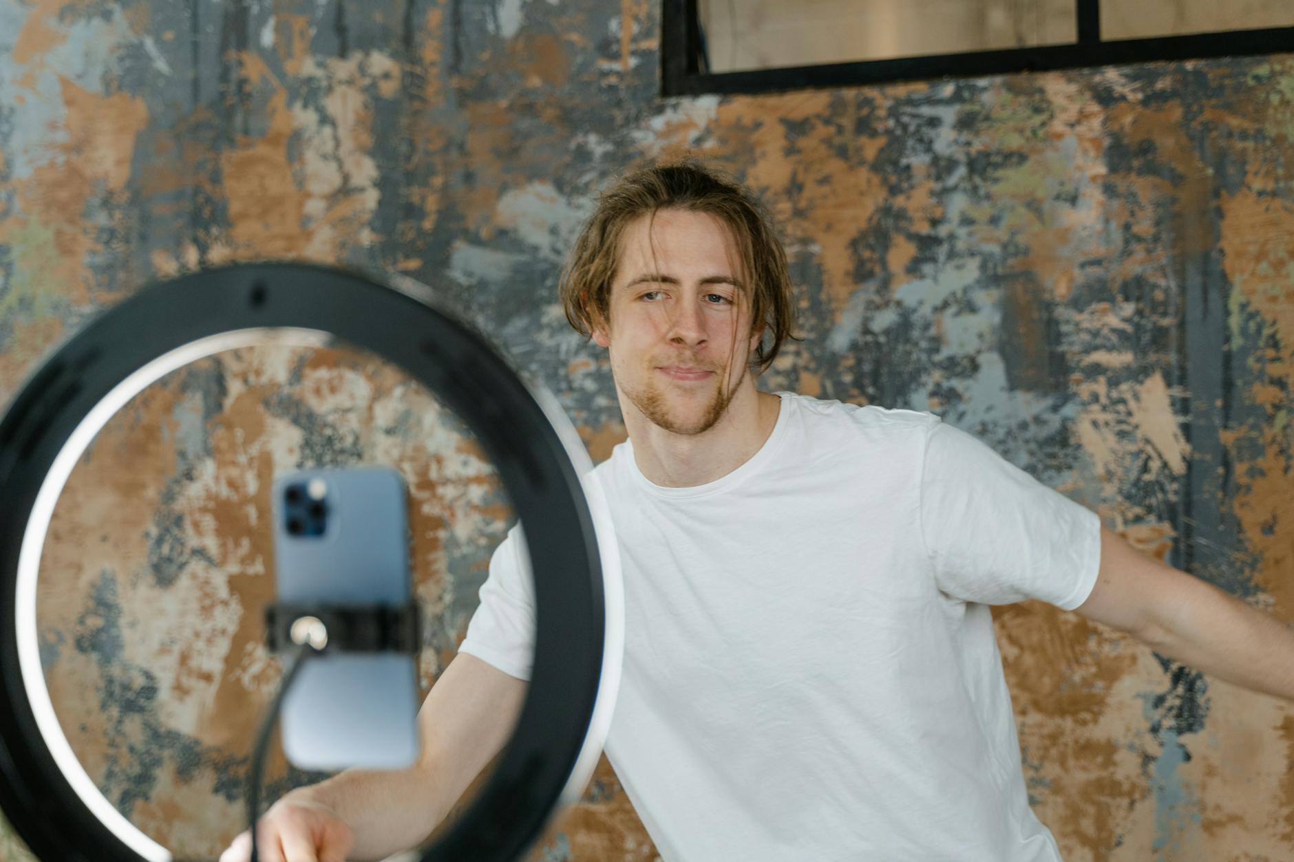 Mężczyzna nagrywający vloga telefonem przy ring light w biurze