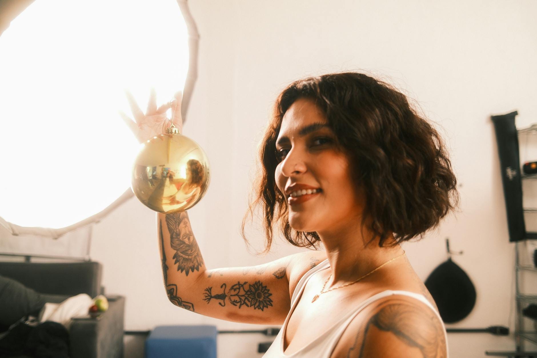 Uśmiechnięta, wytatuowana kobieta trzyma złoty rekwizyt w świetle studyjnym