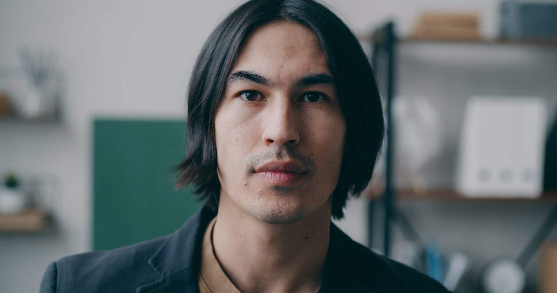 Zamyślony mężczyzna z długimi włosami pozuje do biznesowego portretu