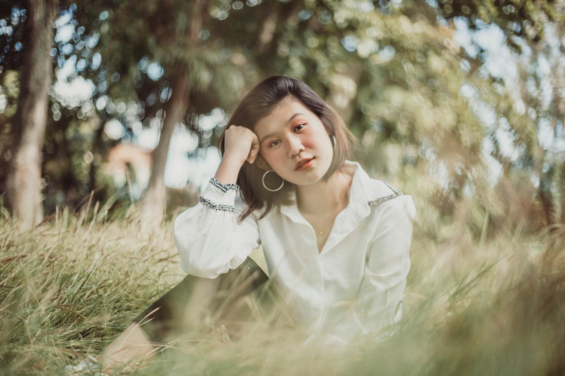 Kobieta siedząca w zielonej łące podczas spokojnej sesji plenerowej