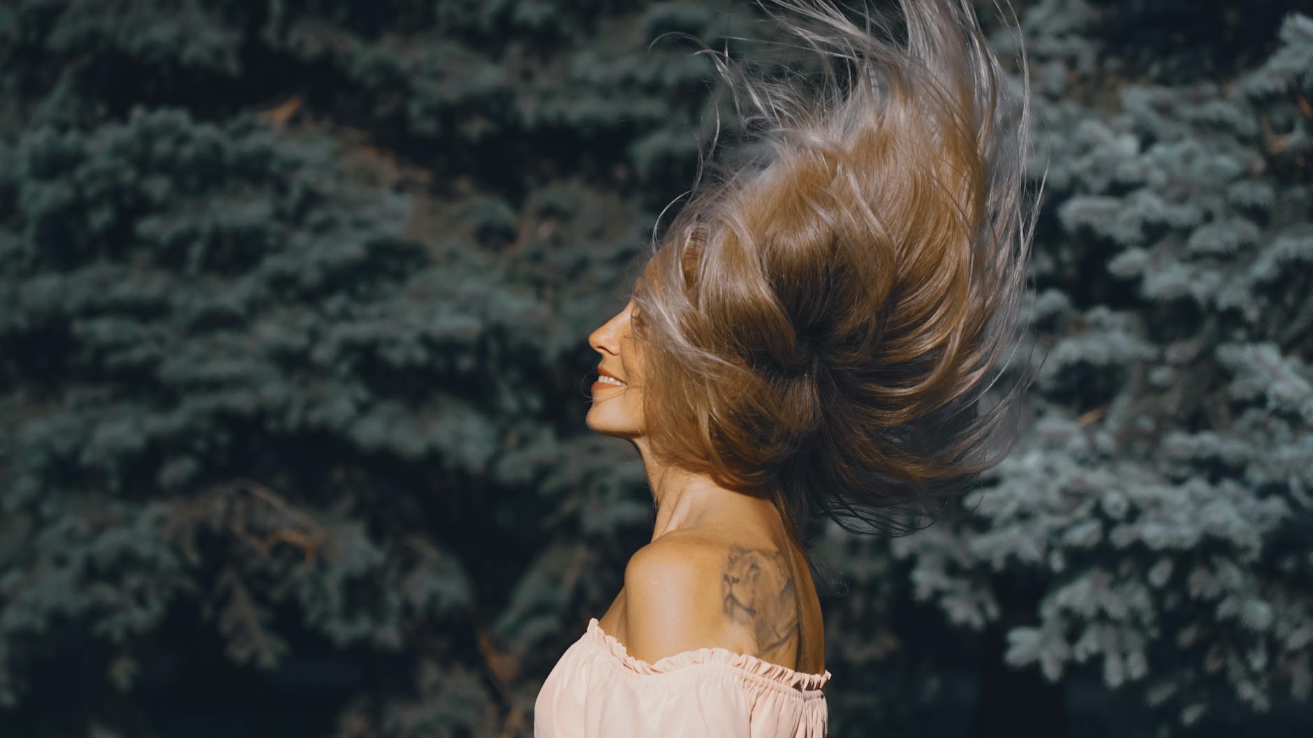 Kobieta w ruchu zarzuca włosami na zewnątrz, dynamiczna poza