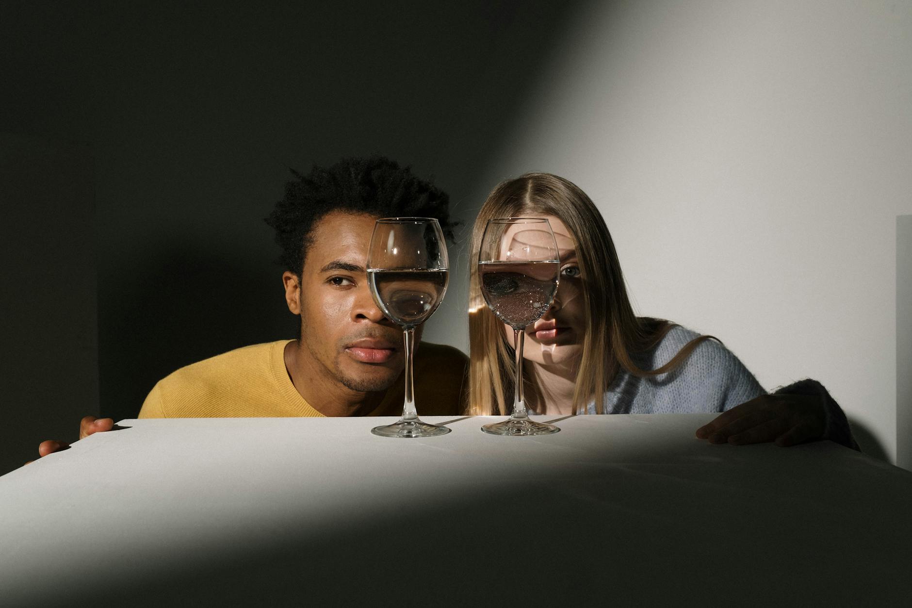 Portret pary w studio z kreatywnymi odbiciami w kieliszkach wina