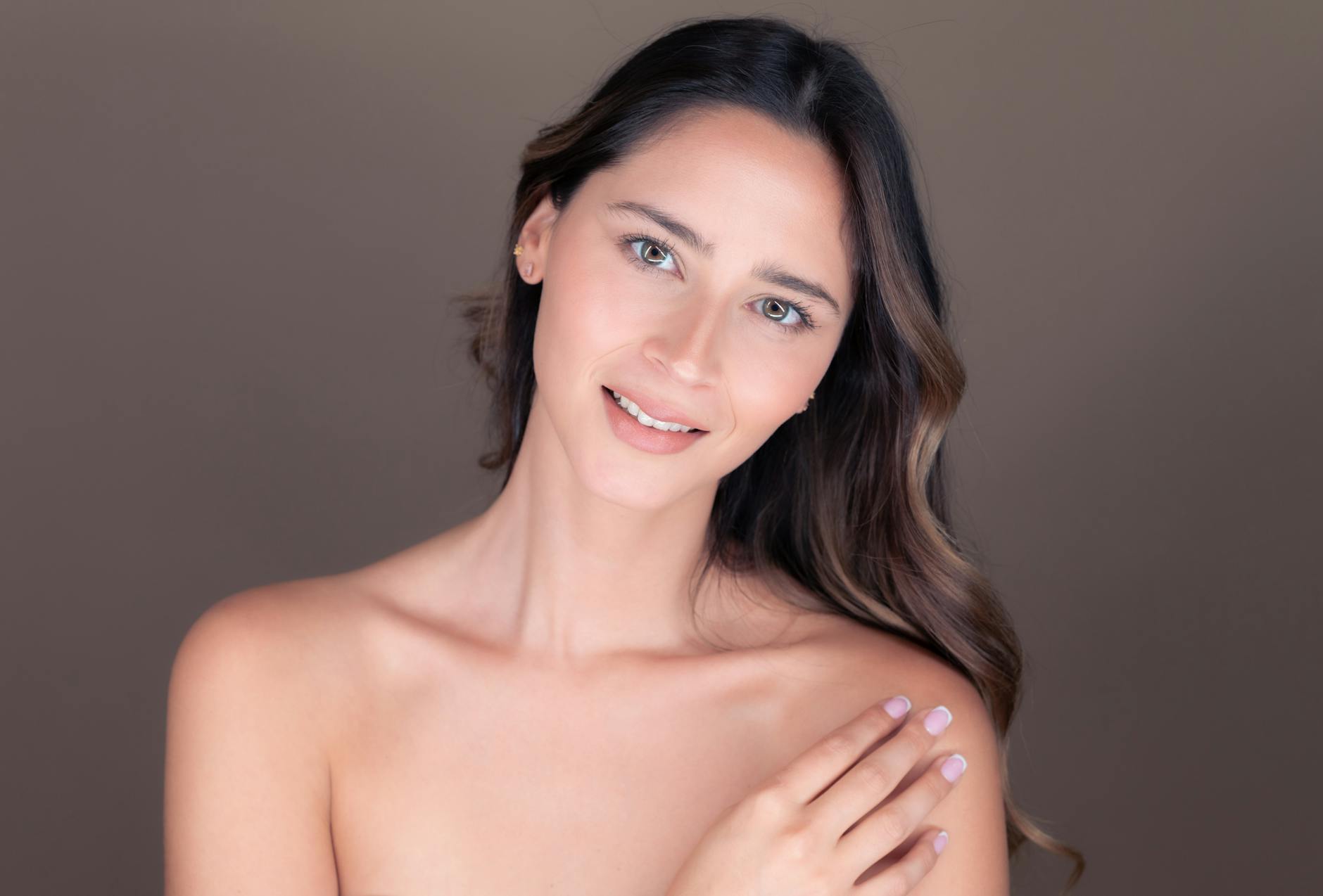 Portret spokojnej brunetki w studio na miękkim szarym tle