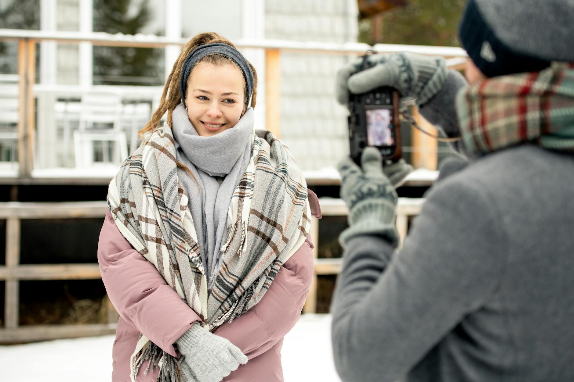 Uśmiechnięta kobieta w zimowym płaszczu pozuje do zdjęcia na dworze