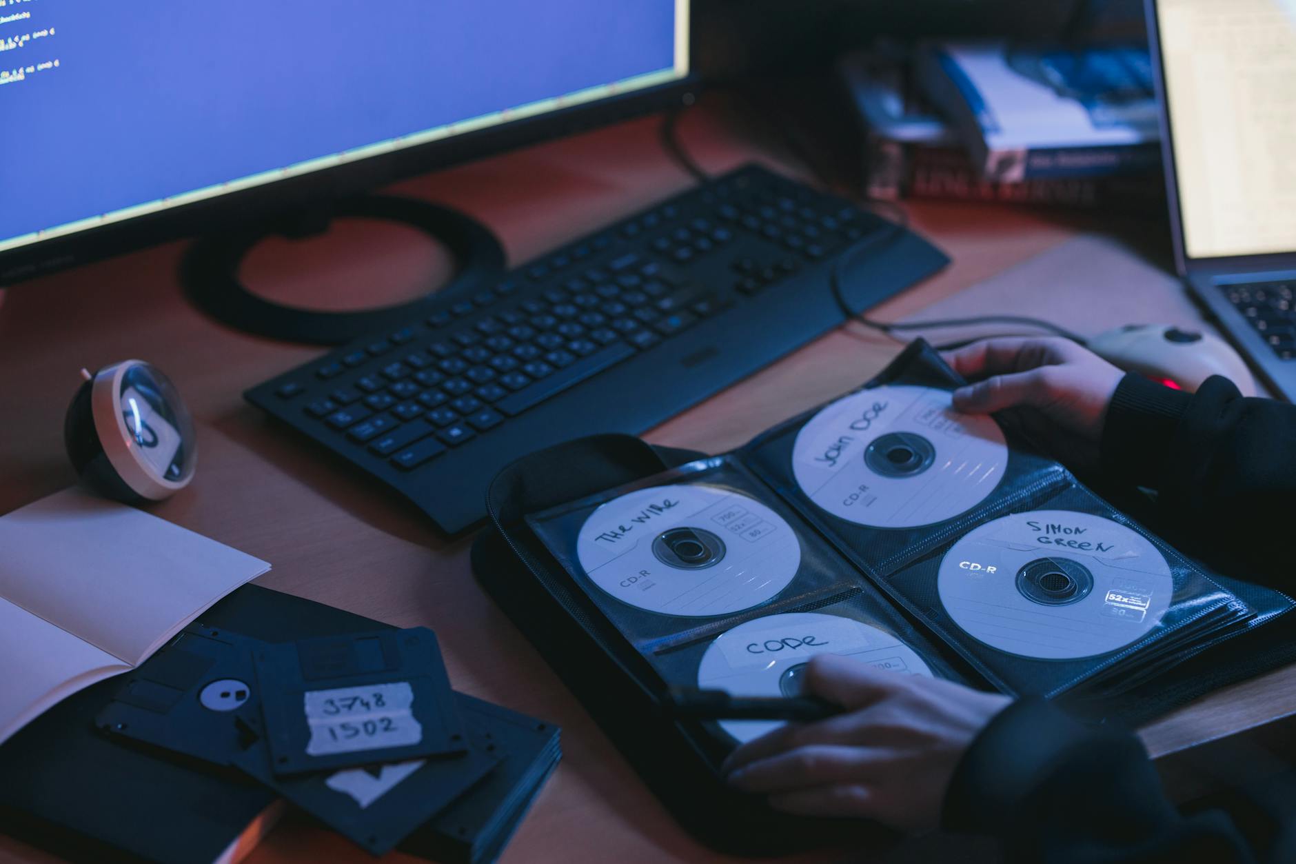 Płyty CD i dyski na biurku w otoczeniu sprzętu komputerowego