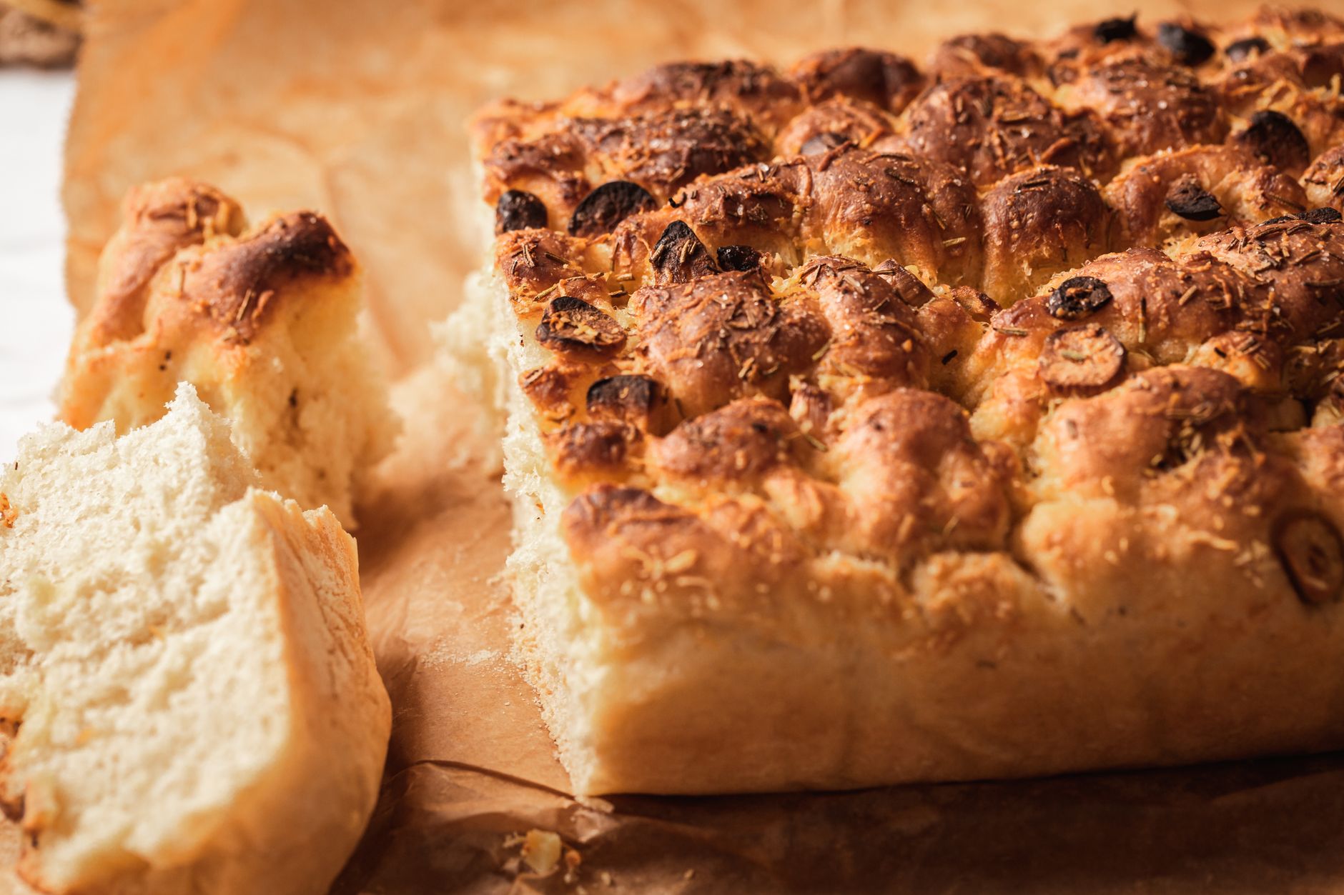 Zbliżenie na świeżo upieczoną focaccię na papierze do pieczenia