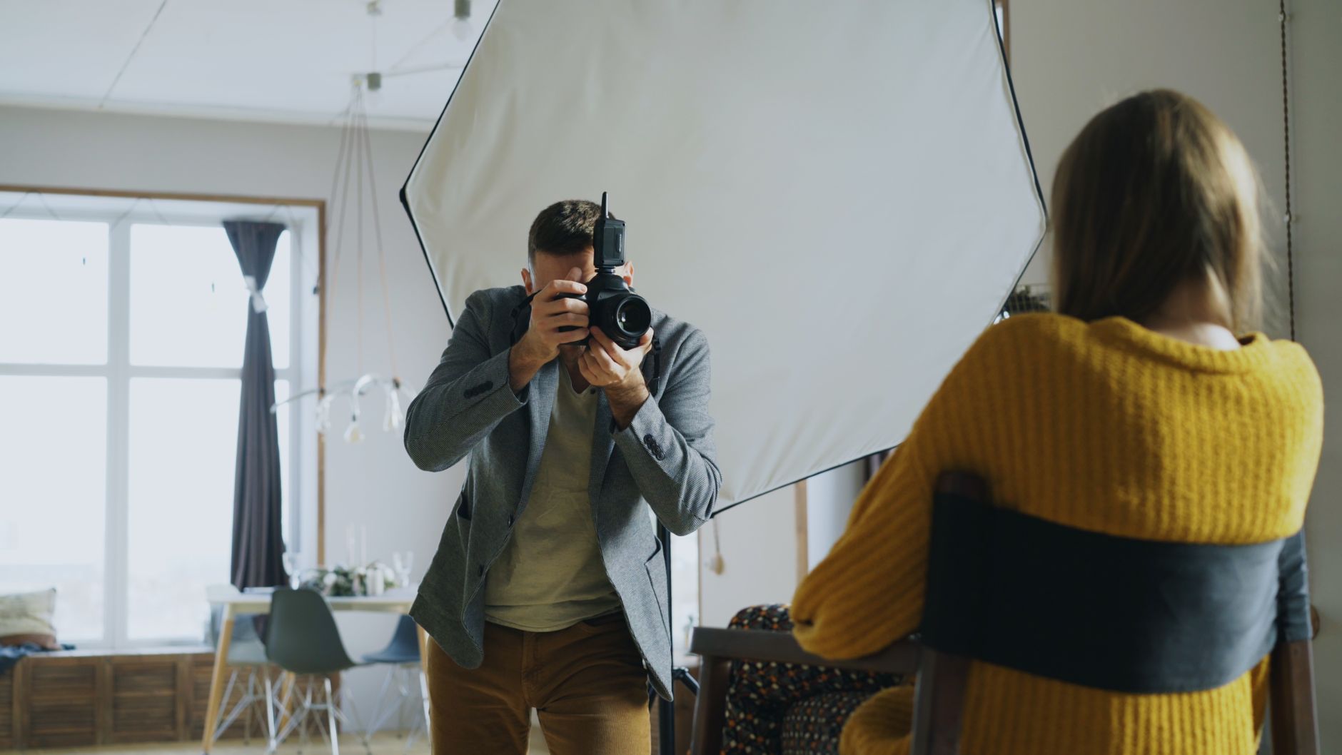 Fotograf wykonuje portret w domowym studio przy świetle dziennym