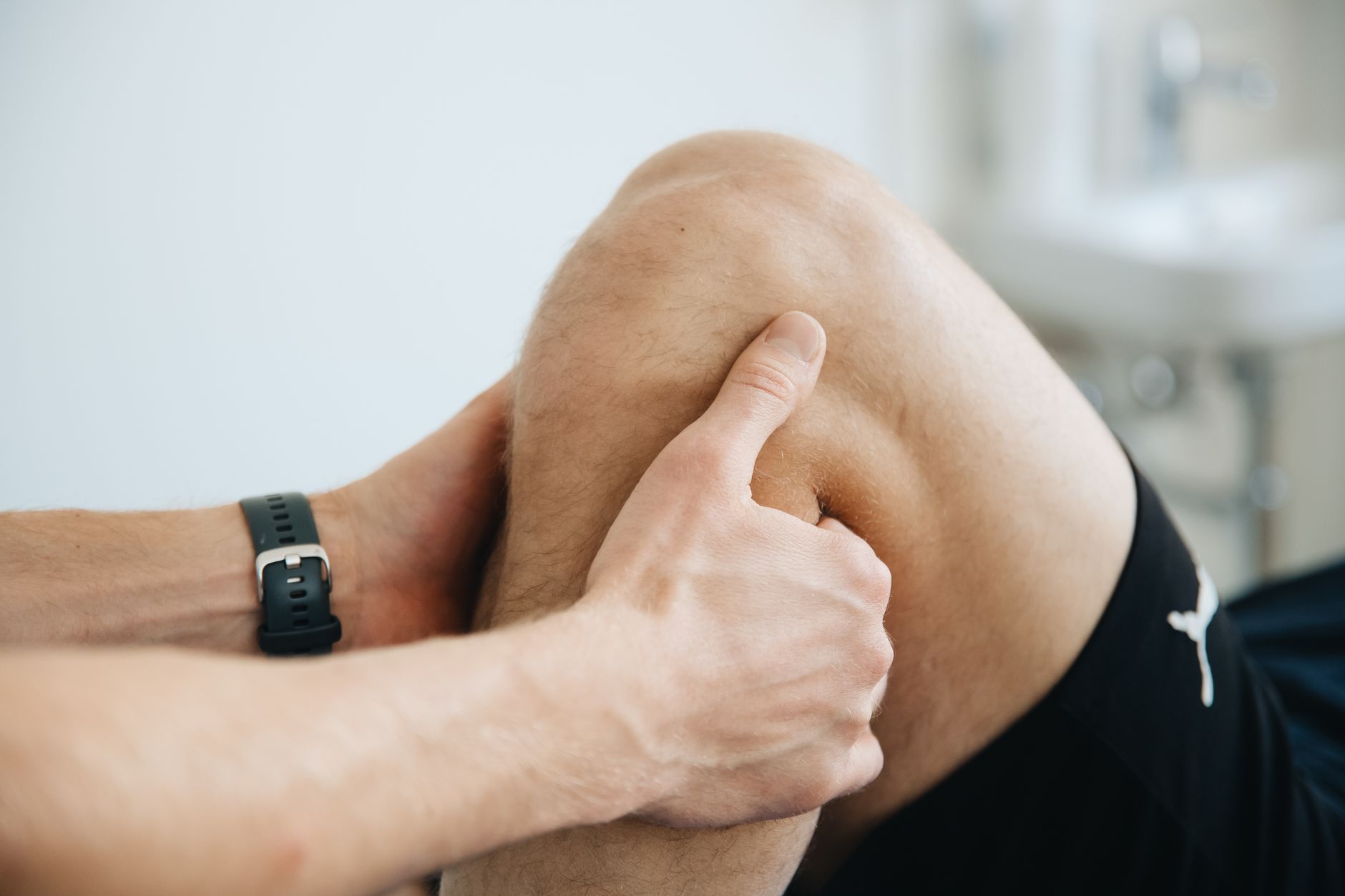Fizjoterapeuta masuje kontuzjowane kolano pacjenta podczas rehabilitacji