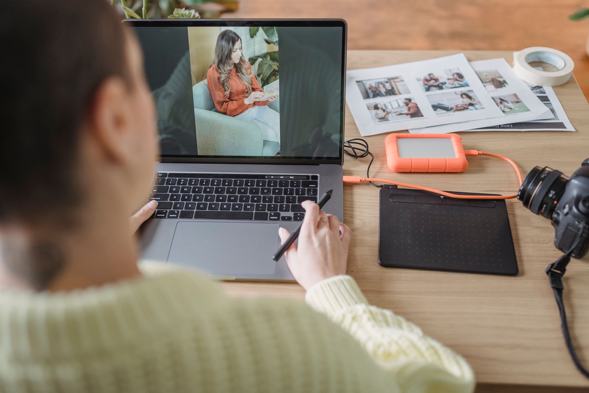 Fotografka przy biurku retuszuje portret na laptopie i tablecie graficznym