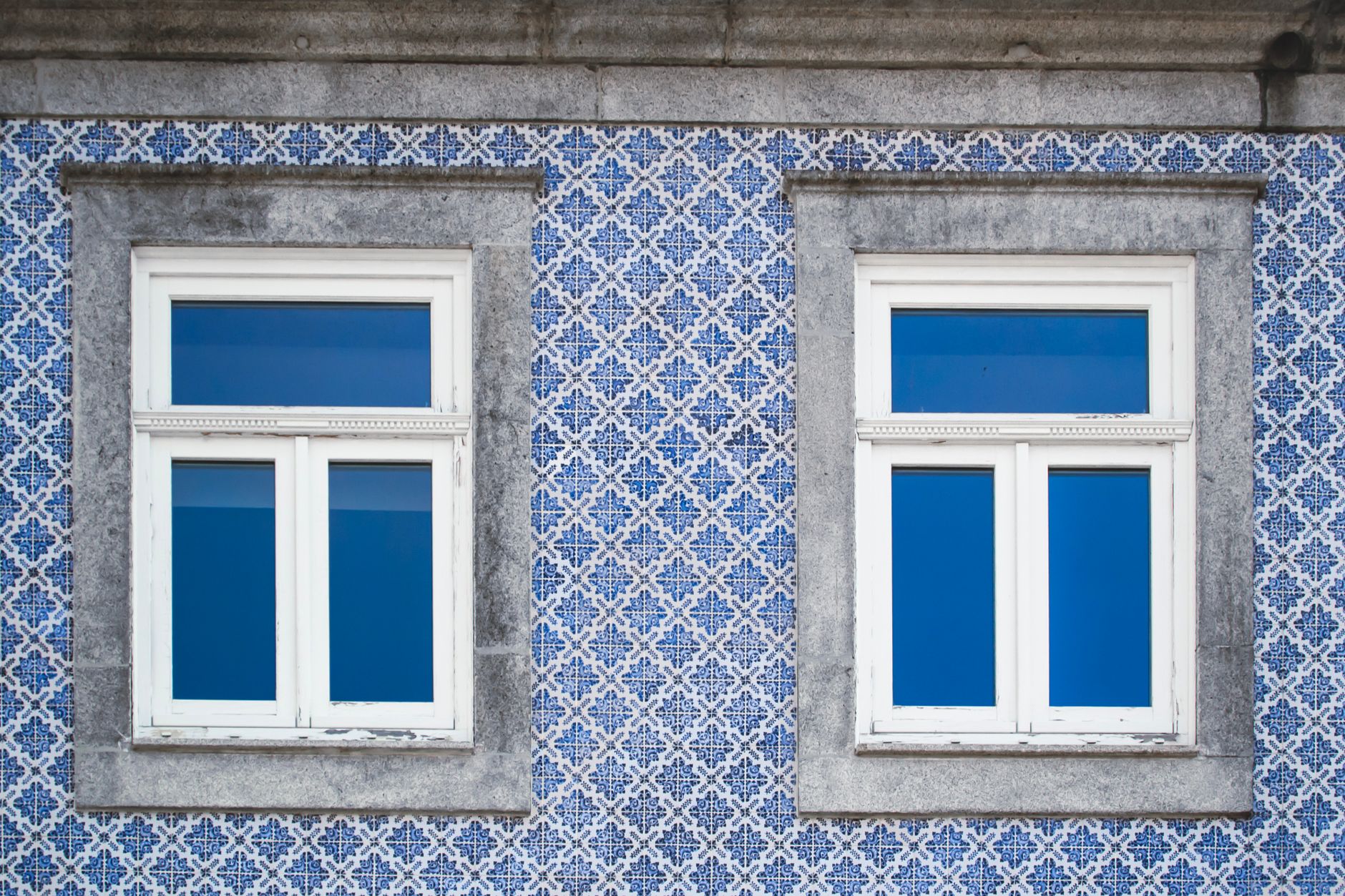 Niebieskie azulejos na fasadzie kamienicy w Porto z białymi oknami